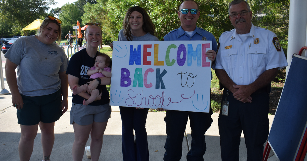 three women a sign and two fire fighters and a baby