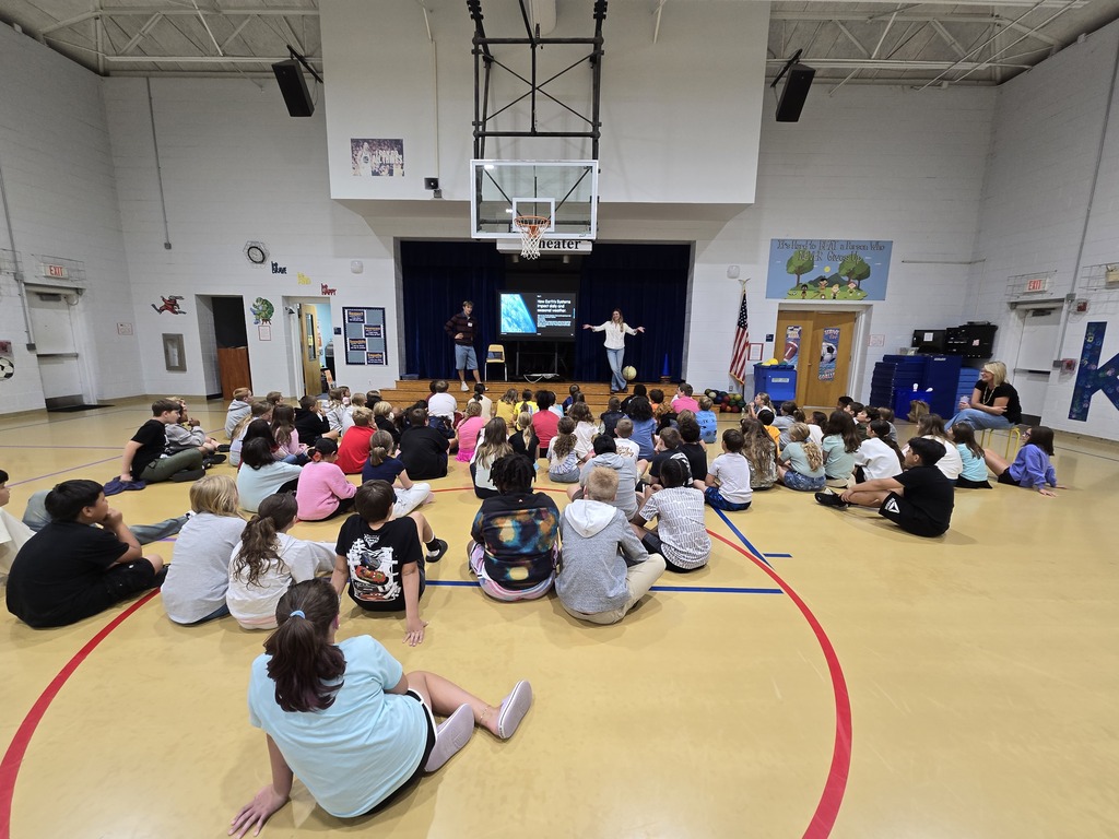 students sit in auditorium, listen to presenters
