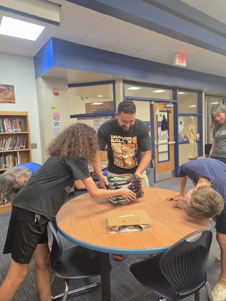 students and staff working on a project around a table in the library 