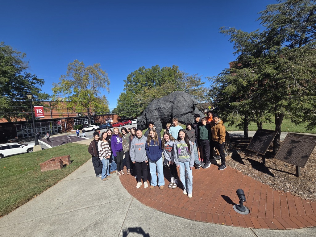 students pose in front of rock