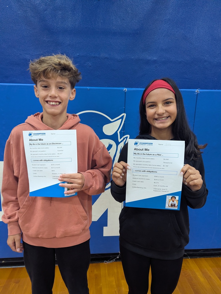 two students hold papers and smile