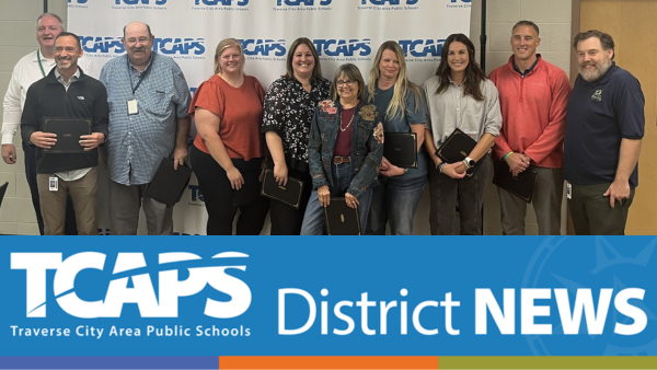 group of individuals smiling and posing for picture in front of TCAPS backdrop.