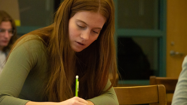 Teenage girl writing on paper at her desk with mechanical pencil.