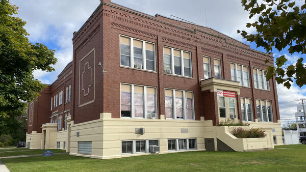 Picture of multi colored brick 2 story building with multiple windows and surrounded by trees