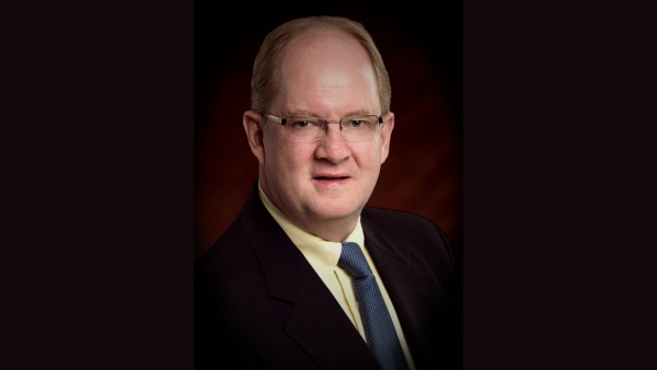 image of man in yellow shirt smiling at the camera wearing glasses