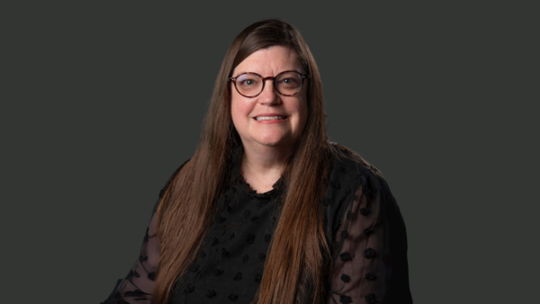 image of woman smiling at camera with long brown hair and wearing glasses