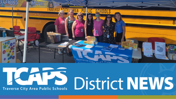 image of seven individuals standing in front of school bus under canopy posing for picture.