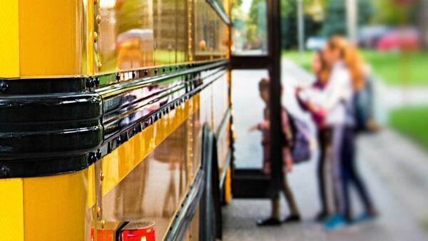image of side of bus with blurred out children entering bus.