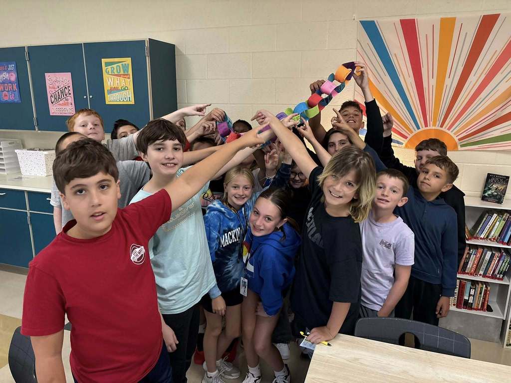 students standing in their classroom holding up their handmade paperchain