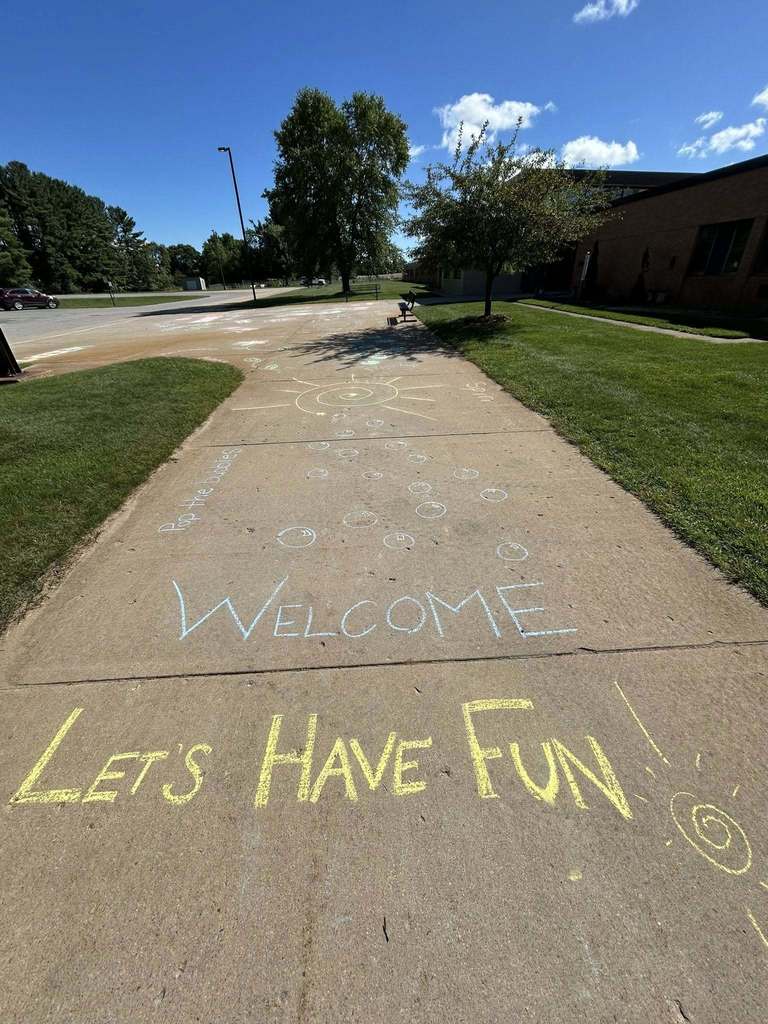 the words welcome lets have fun wrote in chalk outside the school
