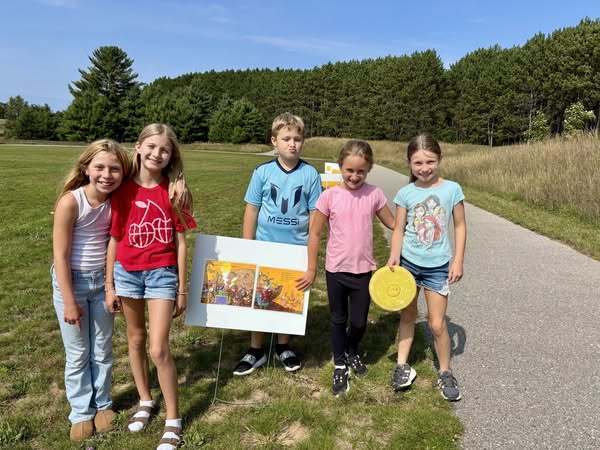 students standing together on a trail in front of a poster with a picture of books on it