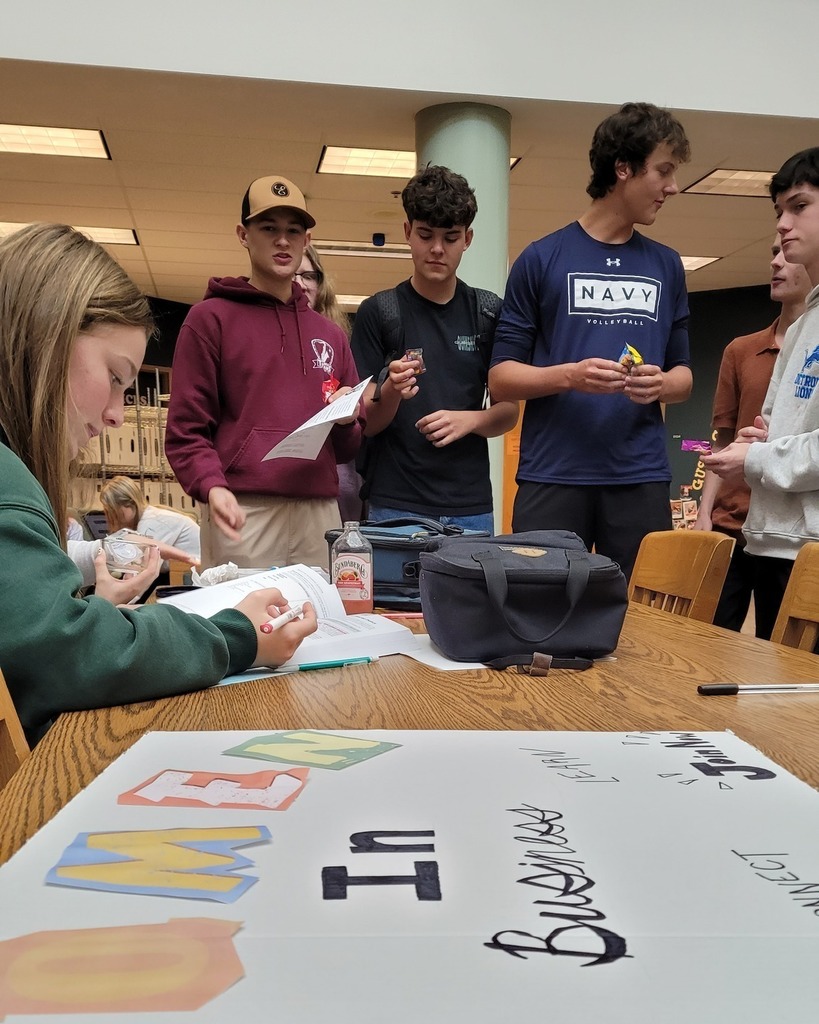 students standing around a table that has material for clubs in the school library