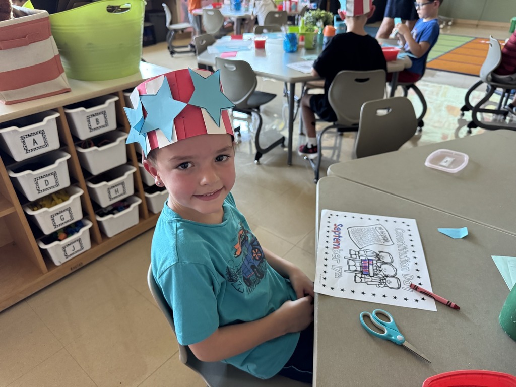 student sitting at his desk wearing a paper hat