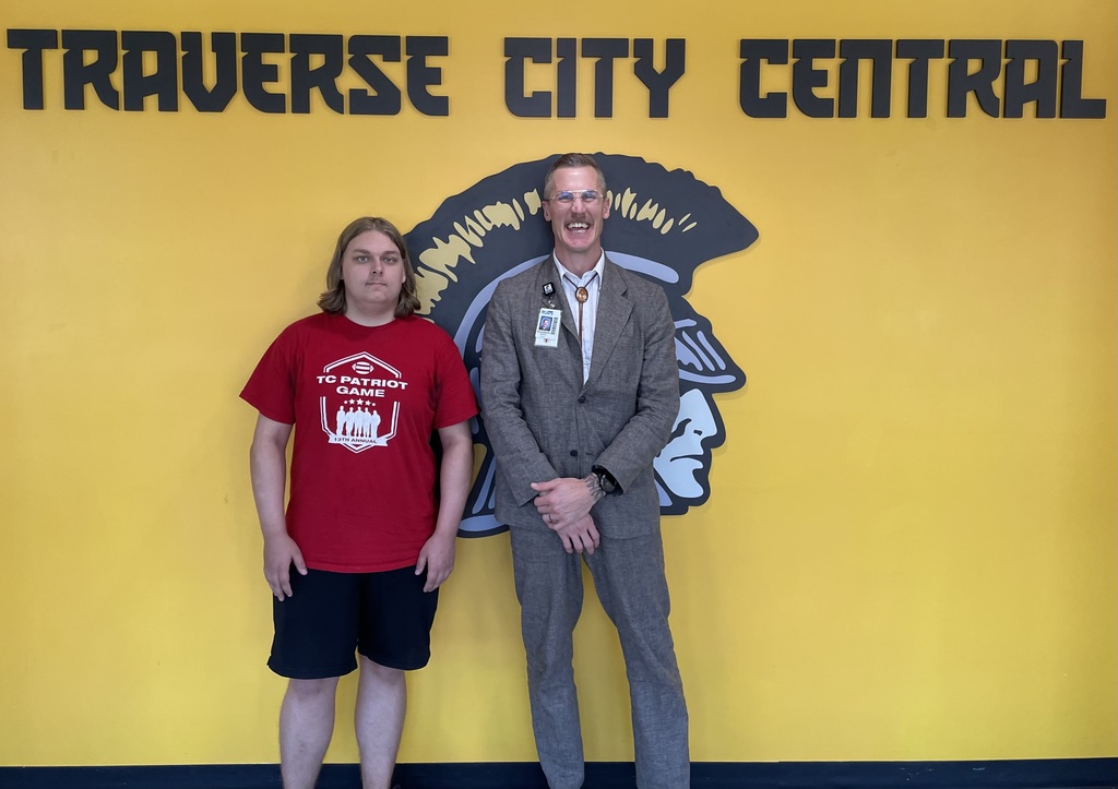 Principal and a student standing in front of a wall in the school hallway