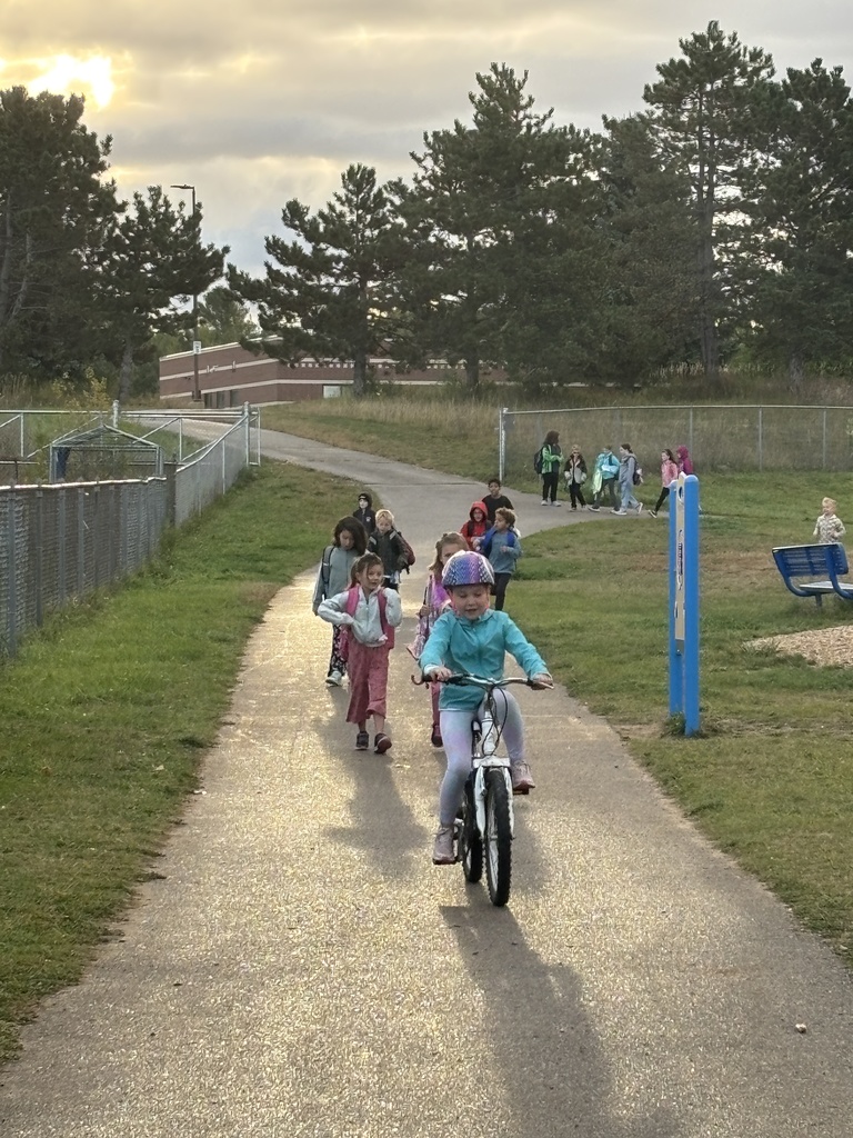 riding bike on track, students walking in background
