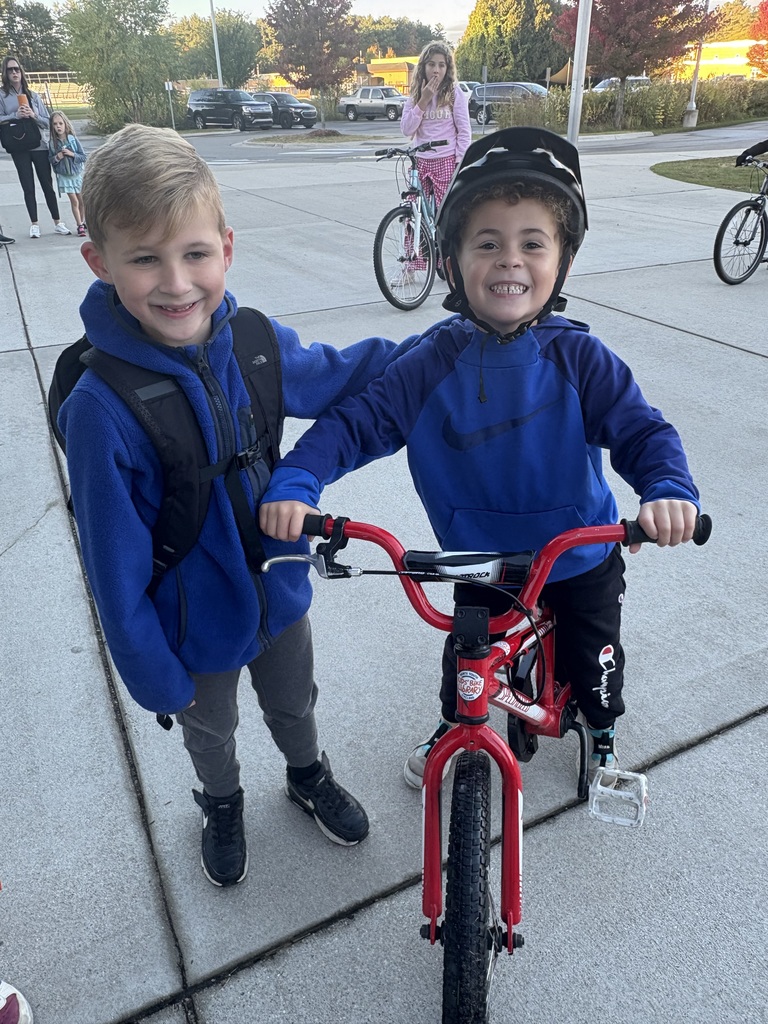 Two students, one on a bike and the other standing aside