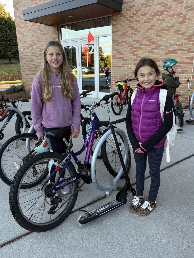 Two students standing by their bike and scooter