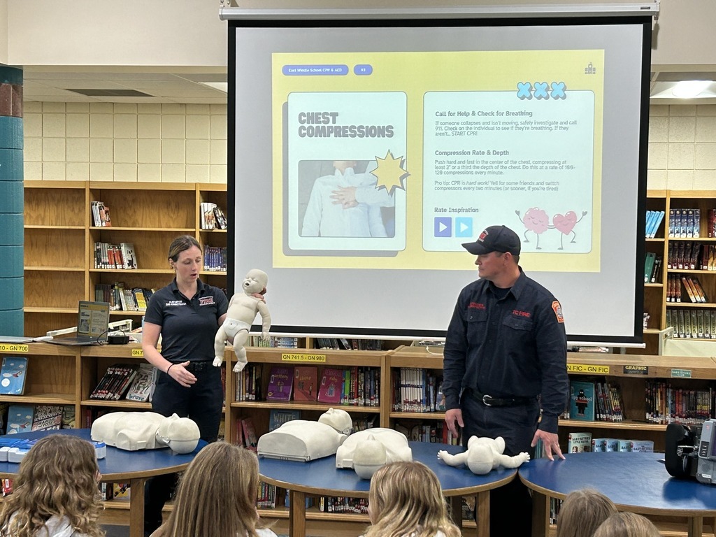 People standing in a room  demonstrating CPR