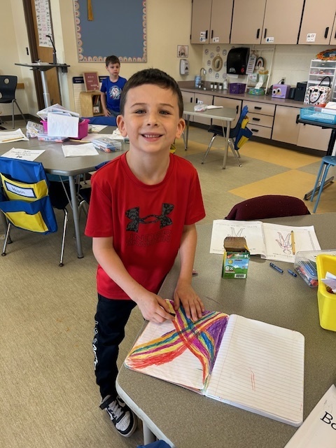 Boy in Red shirt drawning rainbow x's paper