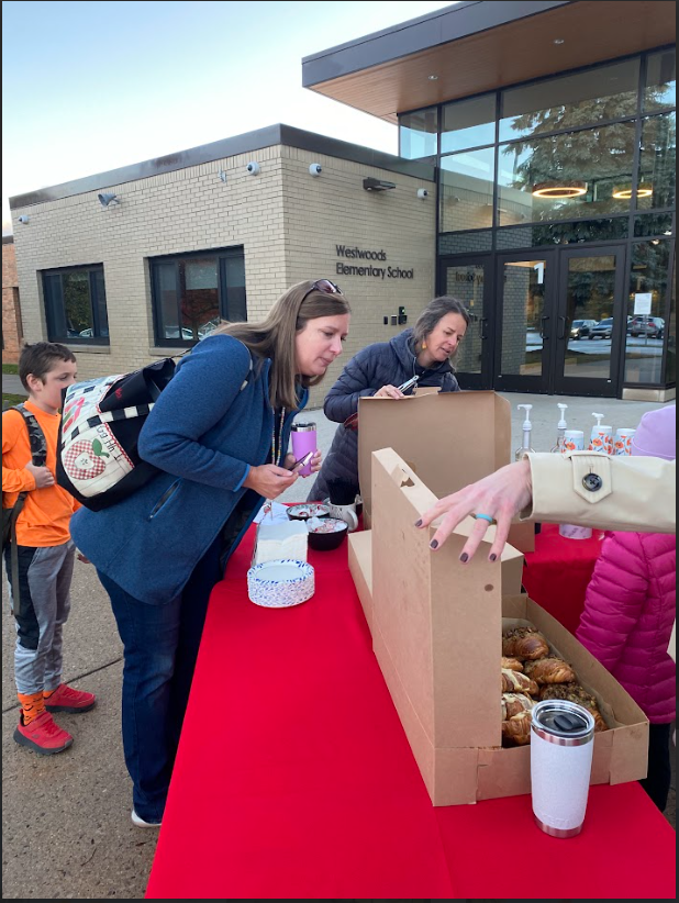 Parent look at Pastries on a table with a red table cloth