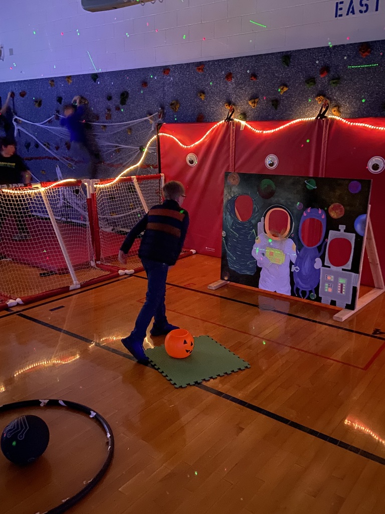 A student throwing a bean bag through a board with space/robot cut outs.