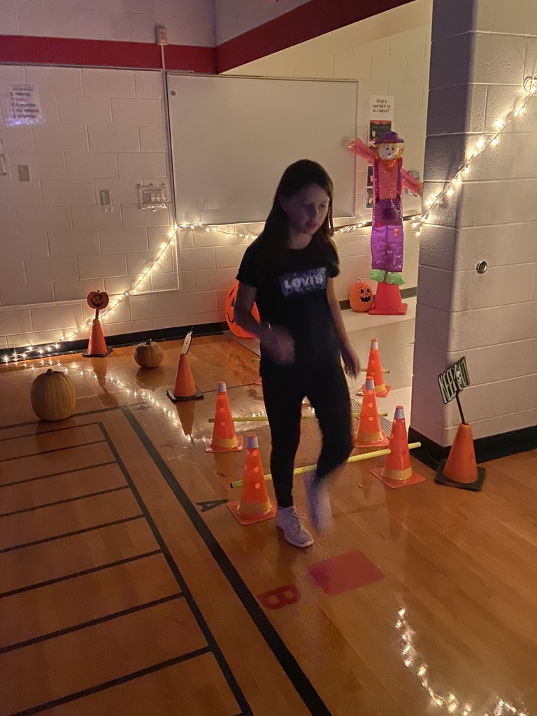 A girl going through an obstacle course with orange cones and hurdles.