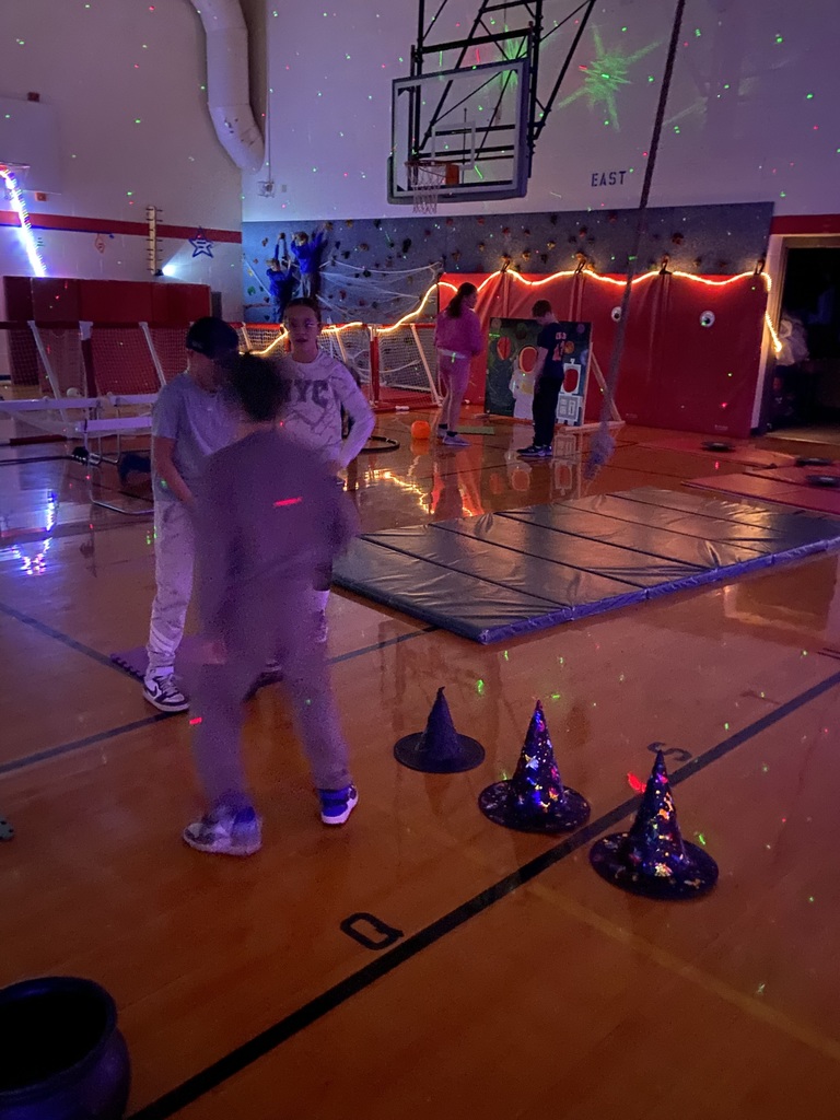 3 students in a halloween obstacle course playing a witch hat game.