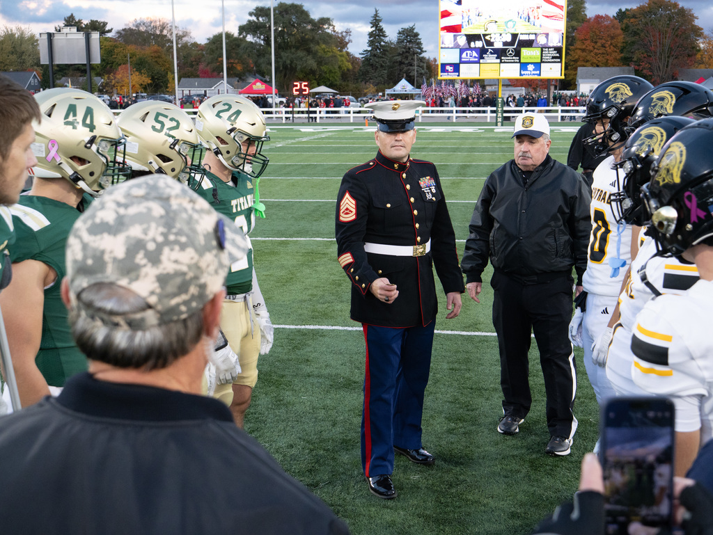 Picture of coin toss before the game. Each team has players present.