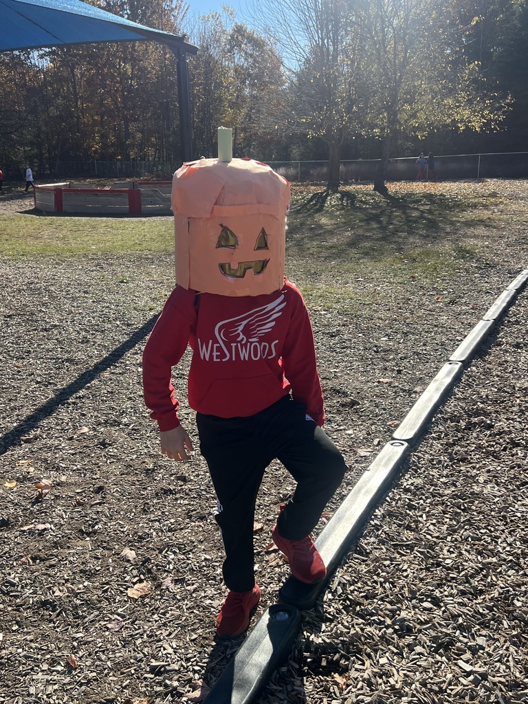 student wearing a red westwoods shirt with a pumpkin mask on his head.