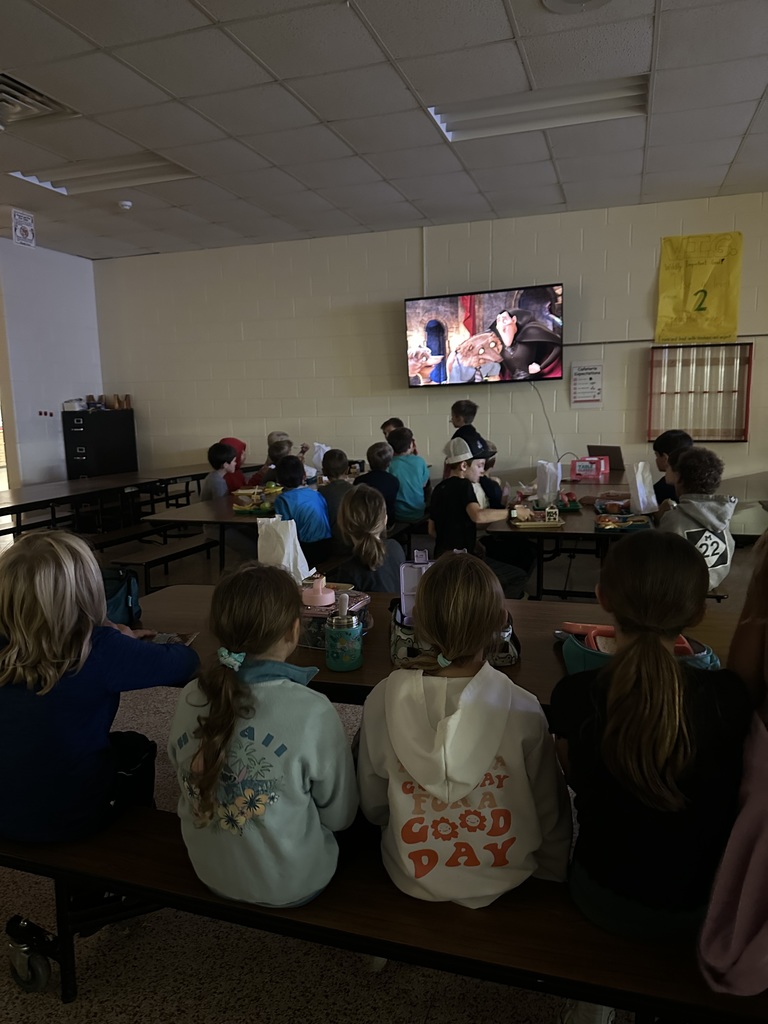 students sitting in the cafeteria, watching a halloween movie.