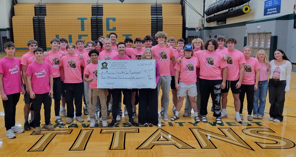 TC West students present a check to the Munson Healthcare Foundation after a "Tackle Cancer" pink game.