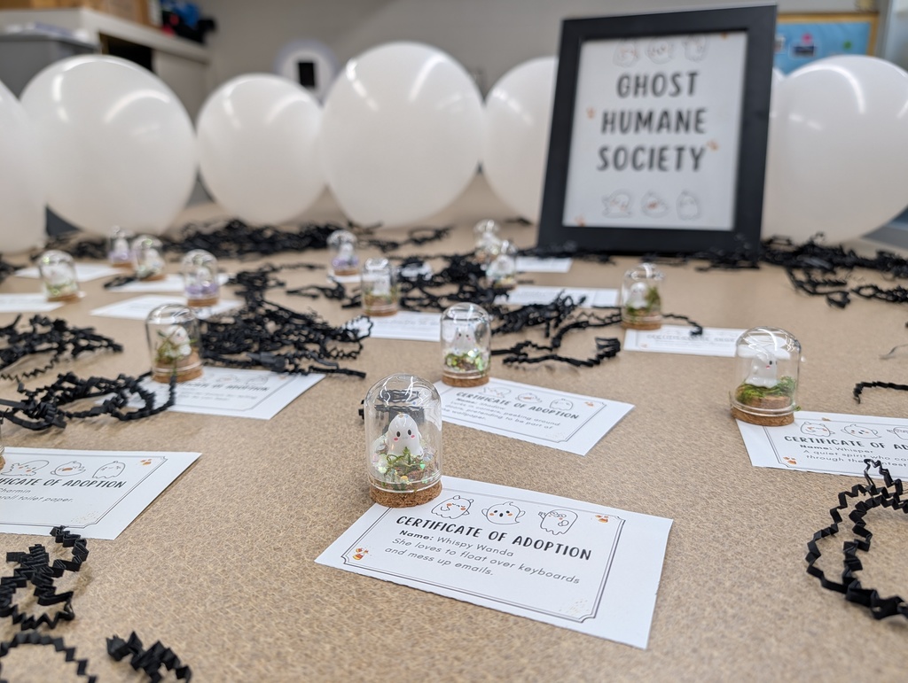 Close-up of small ghost figurines in jars with "Certificate of Adoption" papers for Halloween