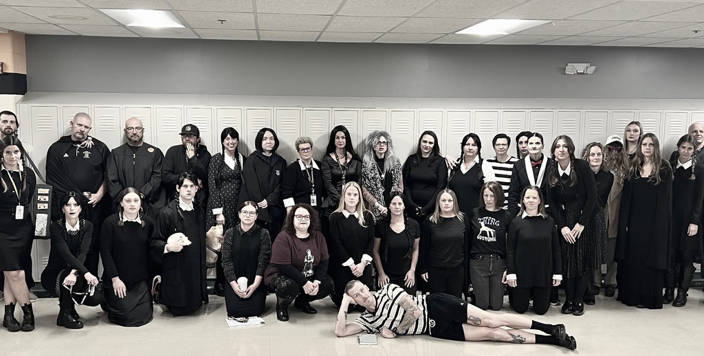 Central High Schools staff dressed in black, some in Addams Family-themed costumes, posing in front of lockers.