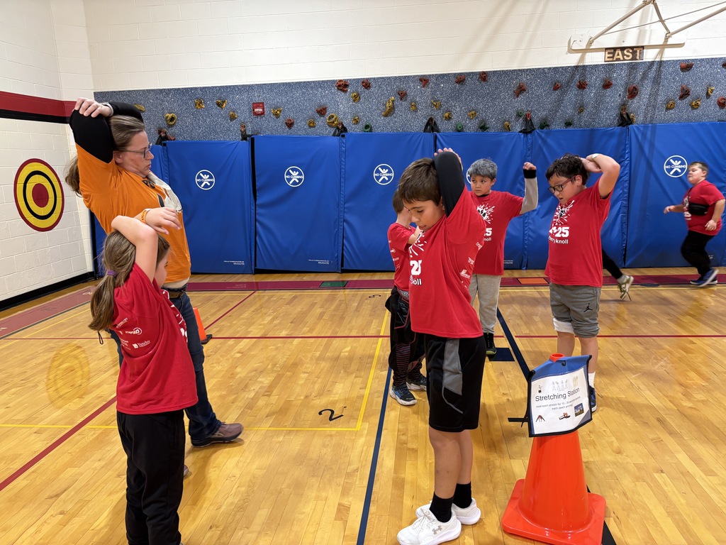 Students and an adult doing arm stretches
