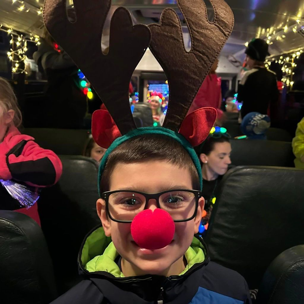 Smiling kid with antlers and red nose