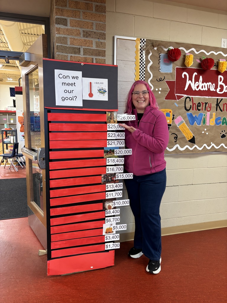 Dr Derks with pink hair standing next to the gift giving thermometer