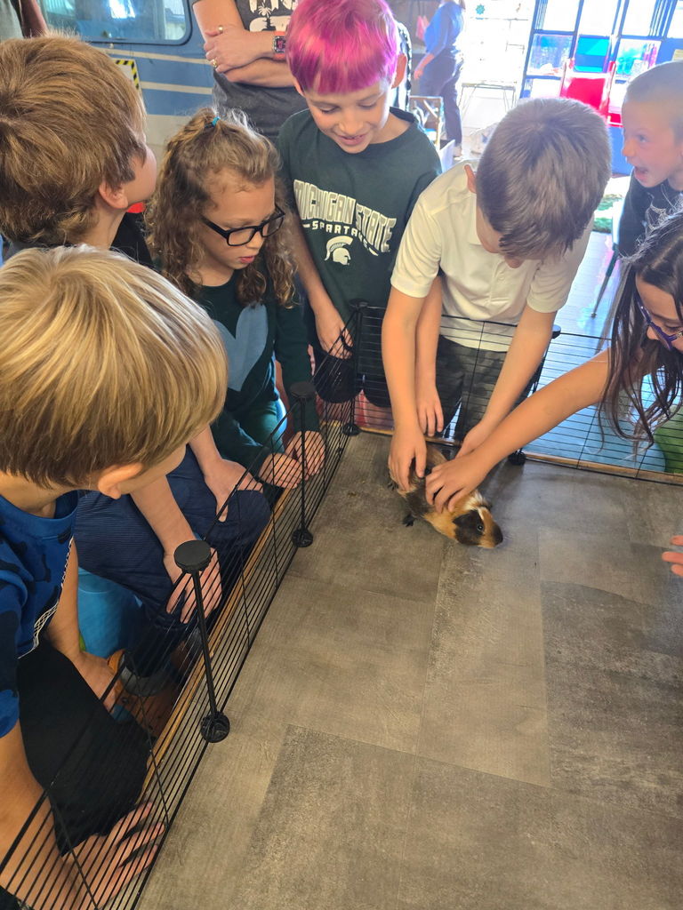 Students surrounding furry creature