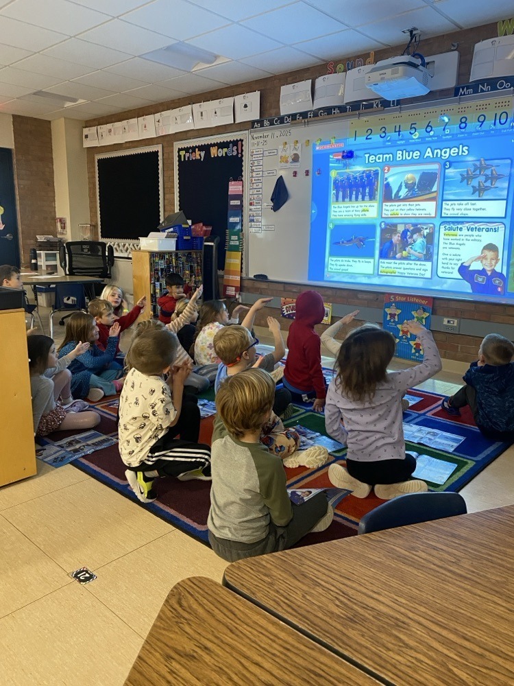 students sitting on the floor saluting