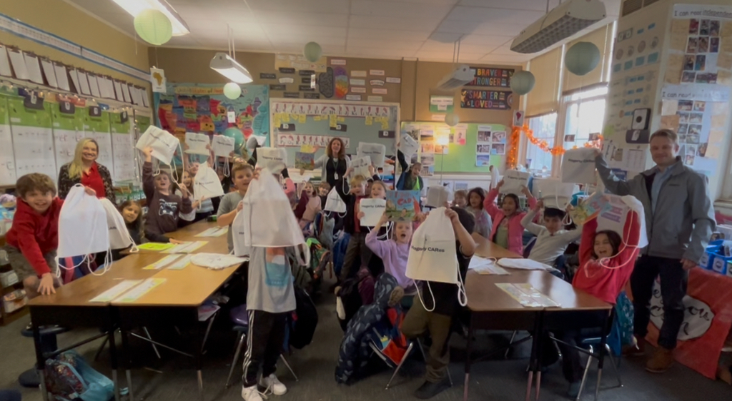 students sitting at their desks holding book bags