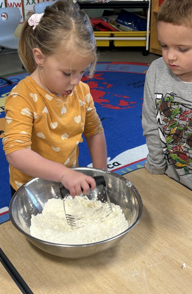 A preschooler cutting butter into flour