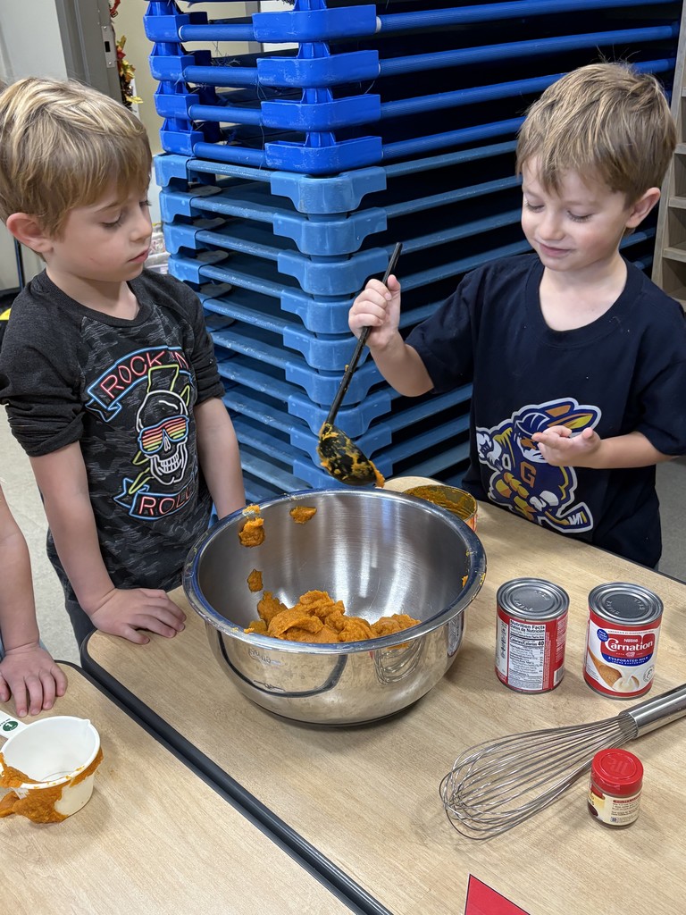 Two preschoolers putting pumpkin in a bowl