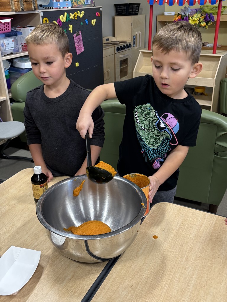 Two preschoolers putting pumpkin in a bowl