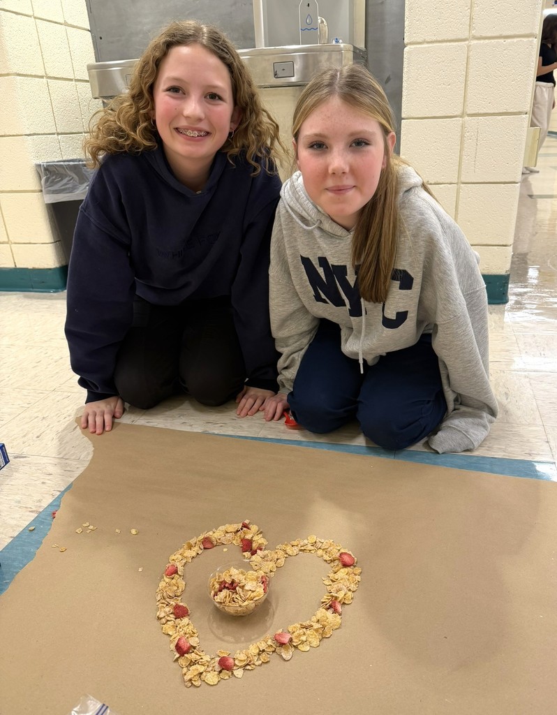 two girls next to a heart made out of cereal