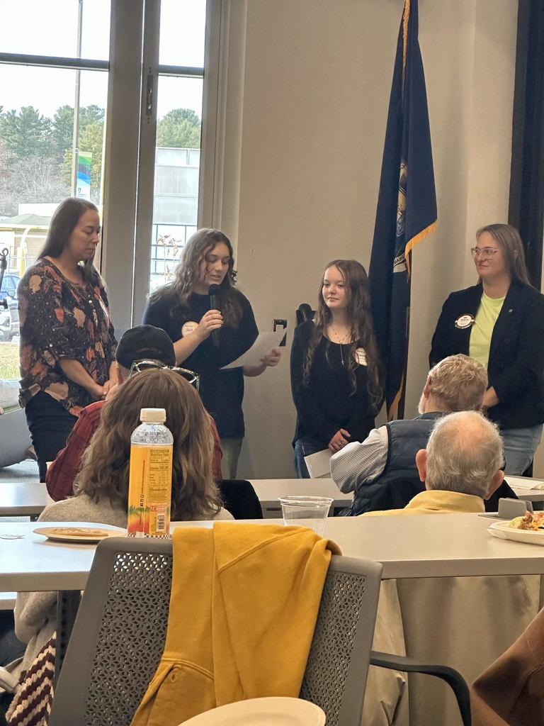 Student making a speech with other people standing in a room