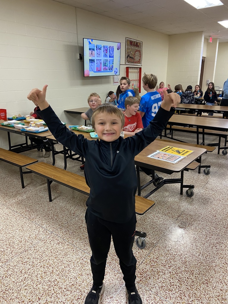student standing with hands up, thumbs up smiling