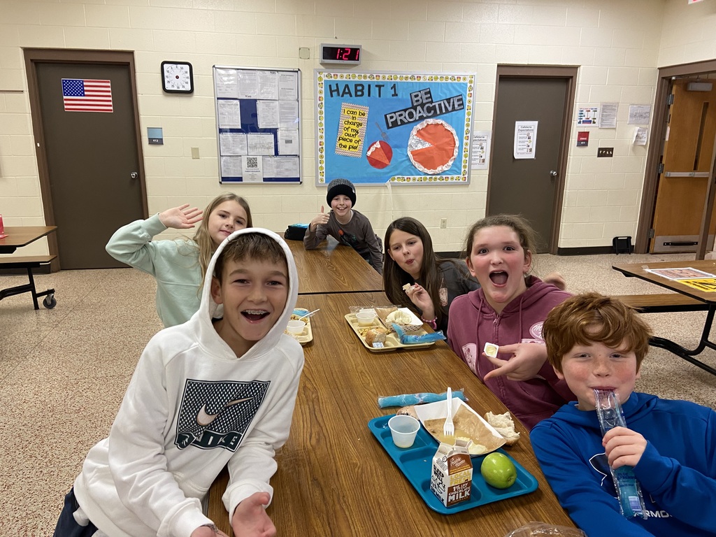 students sitting in the cafeteria, eating and smiling