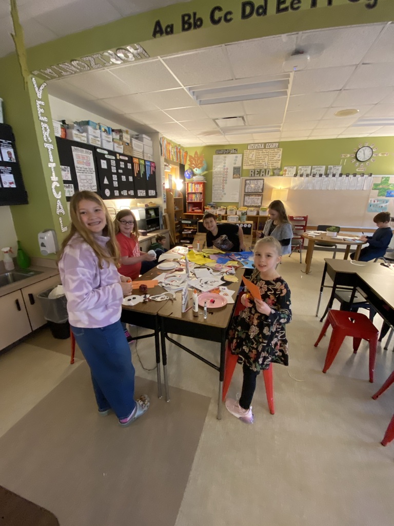 student sitting at a desk smiling, crafting