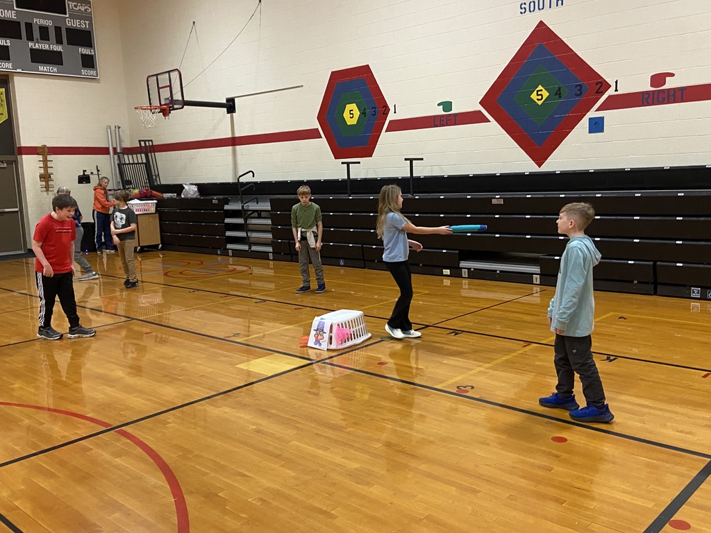 one student guarding the basket with a pool noodle, two other students trying to sneak to the basket to grab the scarf