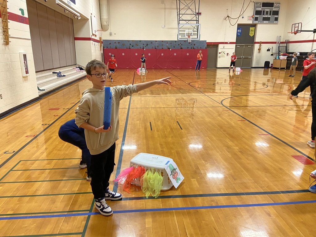 student standing with a pool noodle by a basket with a Tukey print out on the front with scarfs coming out of the side of the basket.