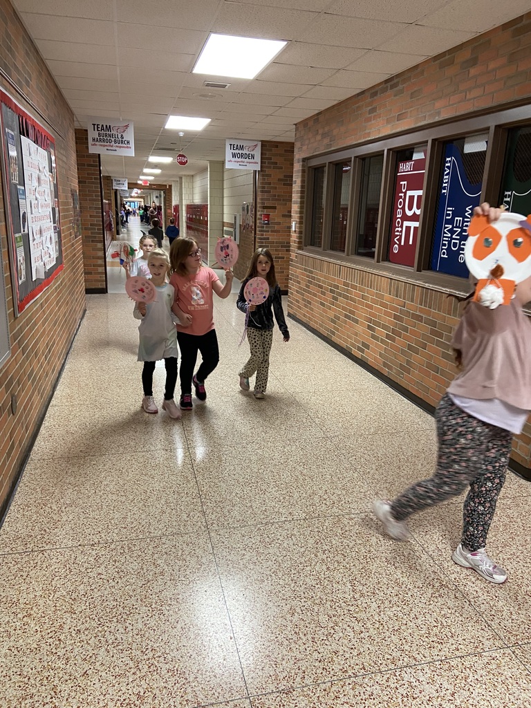 student walking down the hall holding up paper plates that are decorated like balloons